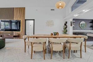 Ein zeitgemäßer Essbereich mit Holztisch und Stühlen, einem Fernseher und einem Wanddekor.