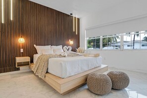 A modern bedroom with a large bed, bedside tables, and a view of the outdoors. - Waterfront House with Tiki & Firepit (Miami)
