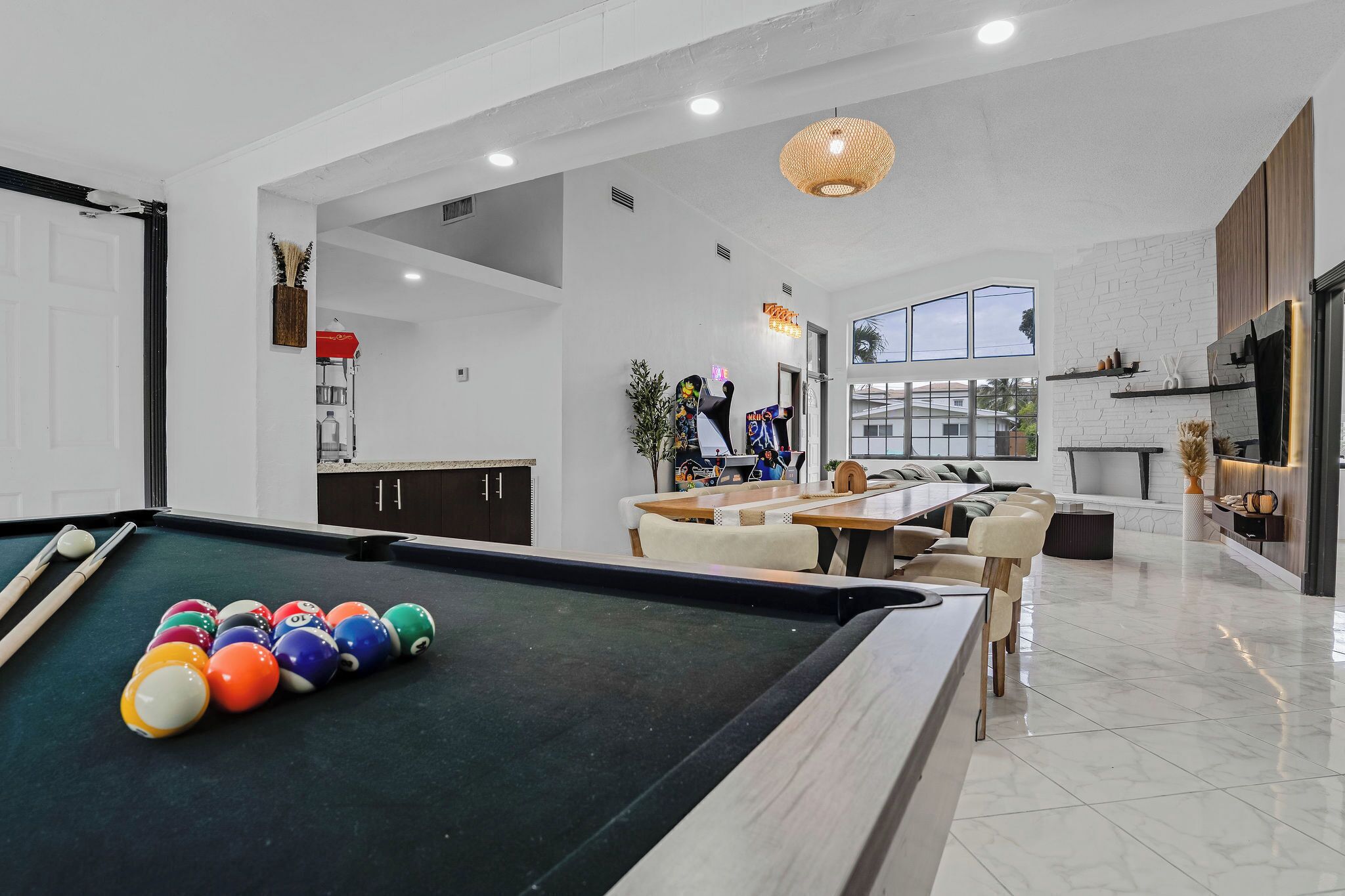 Uma sala de estar moderna com mesa de bilhar, sofás e área de jantar.