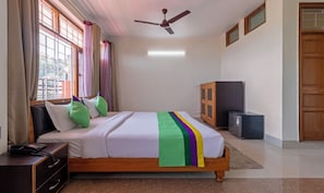 Un dormitorio con cama, ventilador de techo, armario y refrigerador.