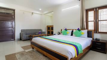 Quarto de hotel com cama, sofá, armário de madeira e janela com cortinas.