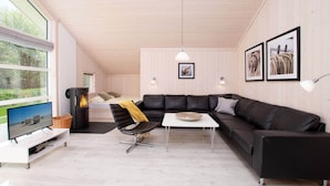 A modern living room with a sectional sofa, a small table, a TV, and a fireplace. - Kustenparadies fur 8 Gaste (Grossenbrode)