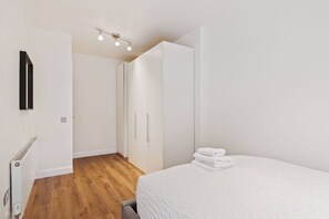 A bedroom with a bed, a radiator, a wardrobe, and a ceiling light fixture. - Modern City Centre Apt with Balcony in Dublin 1 (Dublin)