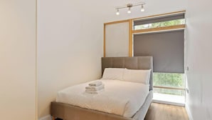 Ein Schlafzimmer mit Bett, Fenster und Deckenleuchte.