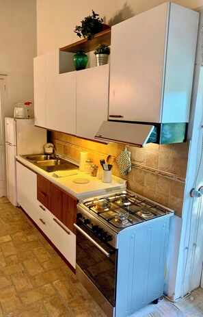 A compact kitchen with white cabinets, a stainless steel stove, and a tiled backsplash. - The Casalino Orvieto Dépendance. A hidden oasis surrounded by greenery, 15 minutes from Orvieto (Umbria)