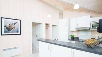 A modern kitchen with white cabinetry, a black countertop, and a framed picture on the wall.
