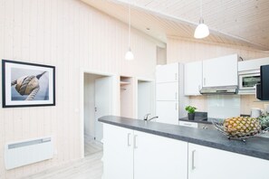 Una cocina moderna con armarios blancos, encimera negra y un cuadro en la pared.