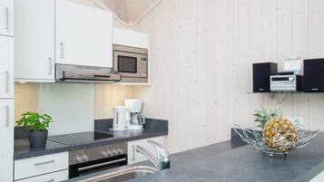 A modern kitchen with white cabinets, a microwave, a coffee maker, and a pineapple on the counter.