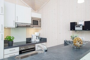 A modern kitchen with white cabinets, a microwave, a coffee maker, and a pineapple on the counter.