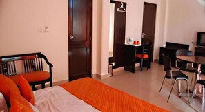 A hotel room with a bed, a desk, a chair, and a door.