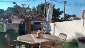 An outdoor wooden table with chairs, a potted plant, and a white umbrella.