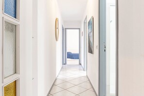 A hallway with a tiled floor, framed artwork on the walls, and a door leading to a room with a bed. - GuestHost - Casa Giovanna, Waterfront, Sea View (Sant'Alessio Siculo)
