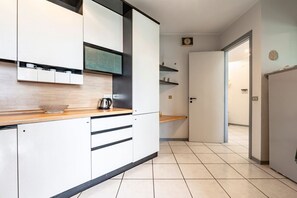 A modern kitchen with white cabinets, a wooden countertop, and a kettle. - GuestHost - Casa Giovanna, Waterfront, Sea View (Sant'Alessio Siculo)