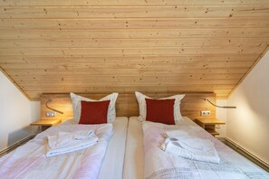 A twin room with wooden ceiling, two beds, bedside tables, and red pillows. - Apartment 'Kuhlmann' with Mountain View and Wi-Fi (Landkreis Goslar)