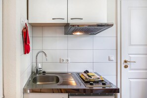 A compact kitchen with a stainless steel sink, a built-in oven, and a white tiled backsplash. - Apartment 'Kuhlmann' with Mountain View and Wi-Fi (Landkreis Goslar)
