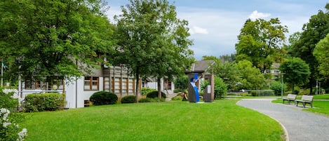 Un parc avec un sentier, des bancs et un bâtiment doté d’une structure bleue.