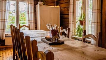 A wooden dining table with chairs, a candle, and a vase with flowers.