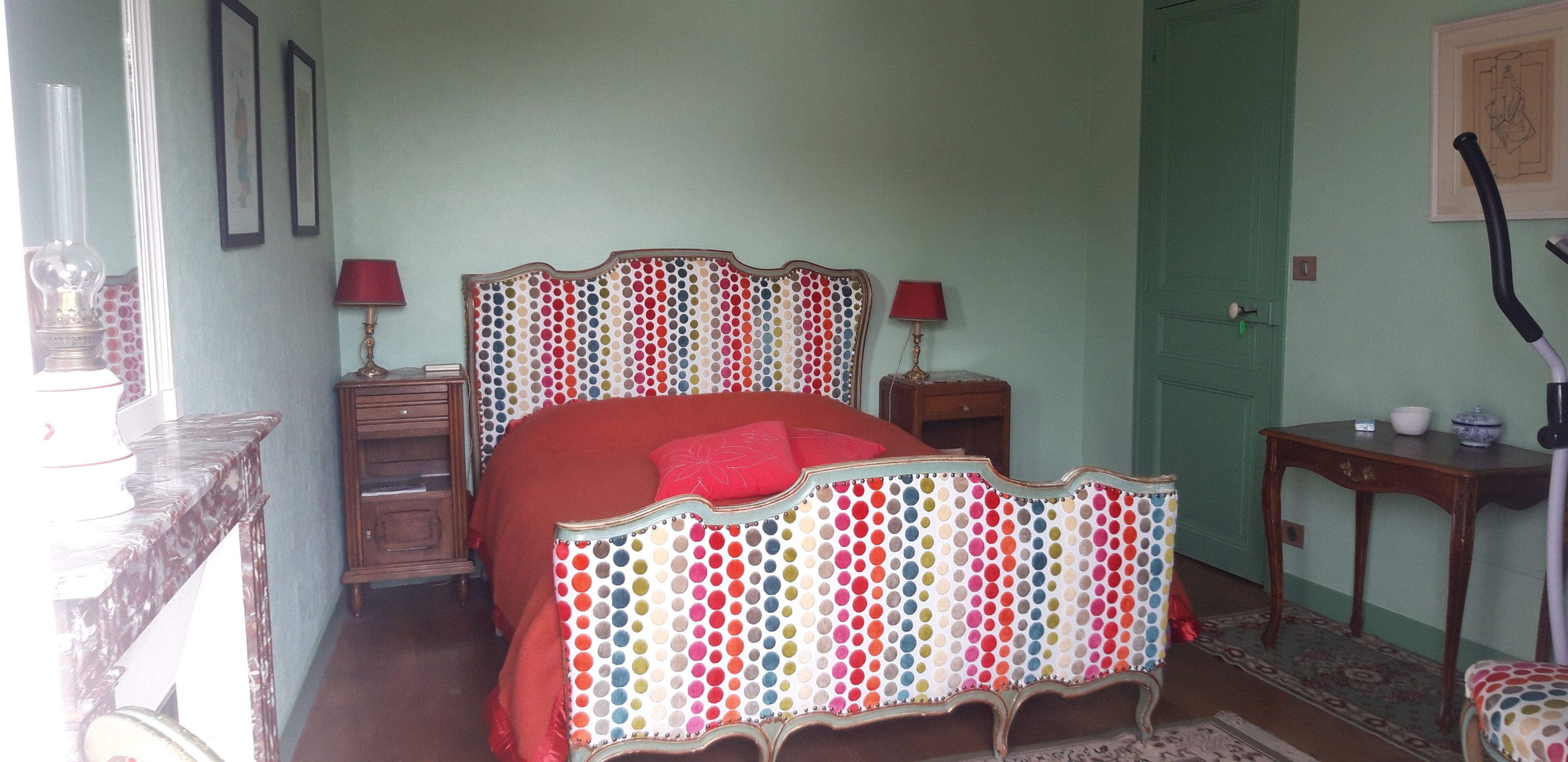 Una camera da letto con un letto, comodini, una lampada e una porta.
