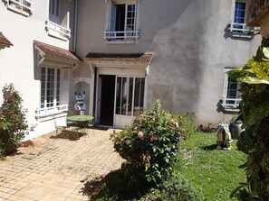 Ein Innenhof mit Terrasse, einer Statue und einem Garten.