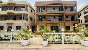 A multi-story building with balconies, a restaurant sign, and potted plants. - RESIDENCE HOTEL YAKRO SUR SEINE (Yamoussoukro)