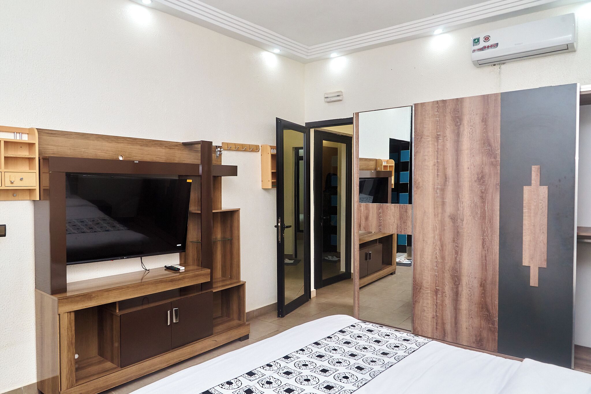 Een slaapkamer met televisie, kledingkast en spiegel.