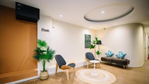 Una sala de estar moderna con un sofá, sillas, una mesa de centro, una lámpara de pie y una planta en maceta.
