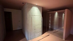 Moderni sisustus, jossa on betonipintainen korosteseinä, lasinen väliseinä ja metallirunkoinen rakenne.