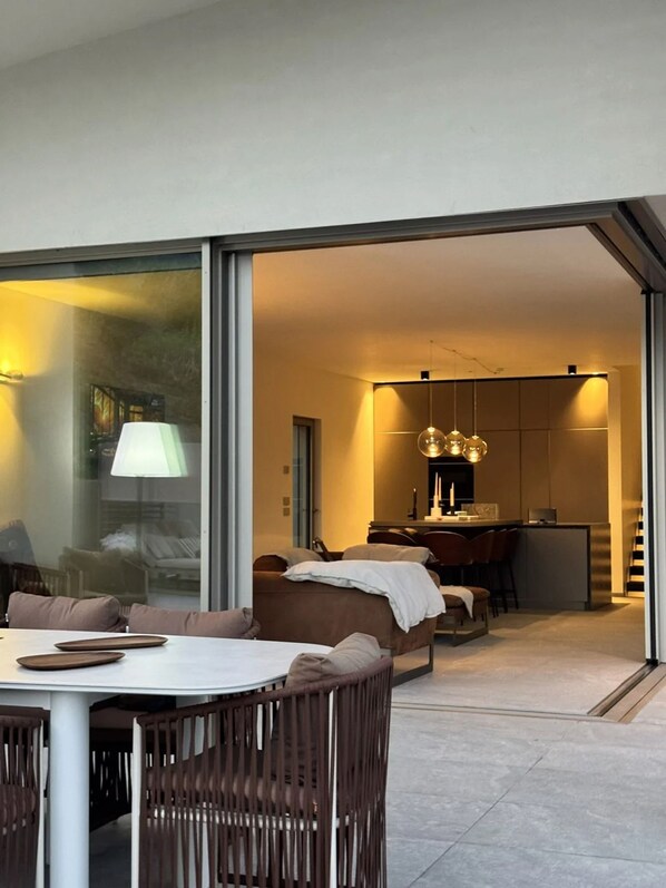 Un espace de vie moderne comprenant un coin repas, une cuisine et une porte-fenêtre coulissante donnant sur un balcon.