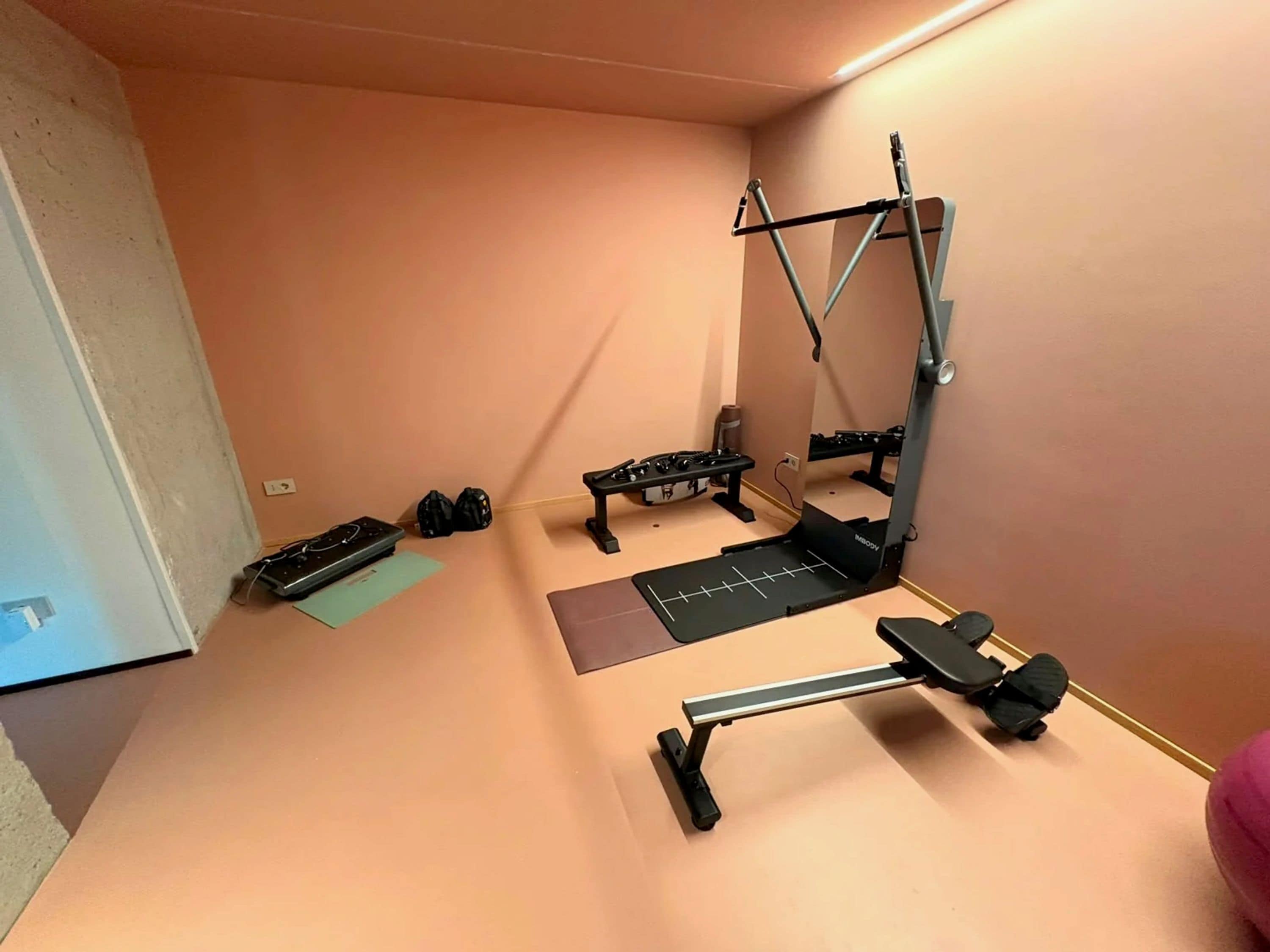 A compact gym with a pull-up bar, bench press, and dumbbells.