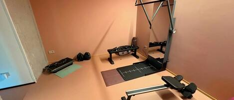 A compact gym with a pull-up bar, bench press, and dumbbells.