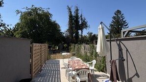 Een terras met een tafel en stoelen, een hangende parasol en een bakstenen muur.