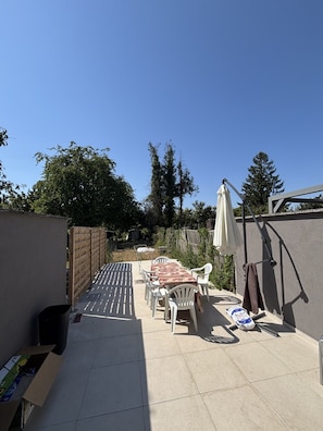 A patio with a table and chairs, a hanging umbrella, and a brick wall. - Family home with a garden. Brussels is a 9-minute train ride away. Near Hallerbos (Halle)