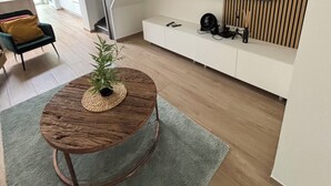 Een moderne woonkamer met een houten salontafel, een flatscreen televisie aan de muur en een trap naar een hoger niveau.
