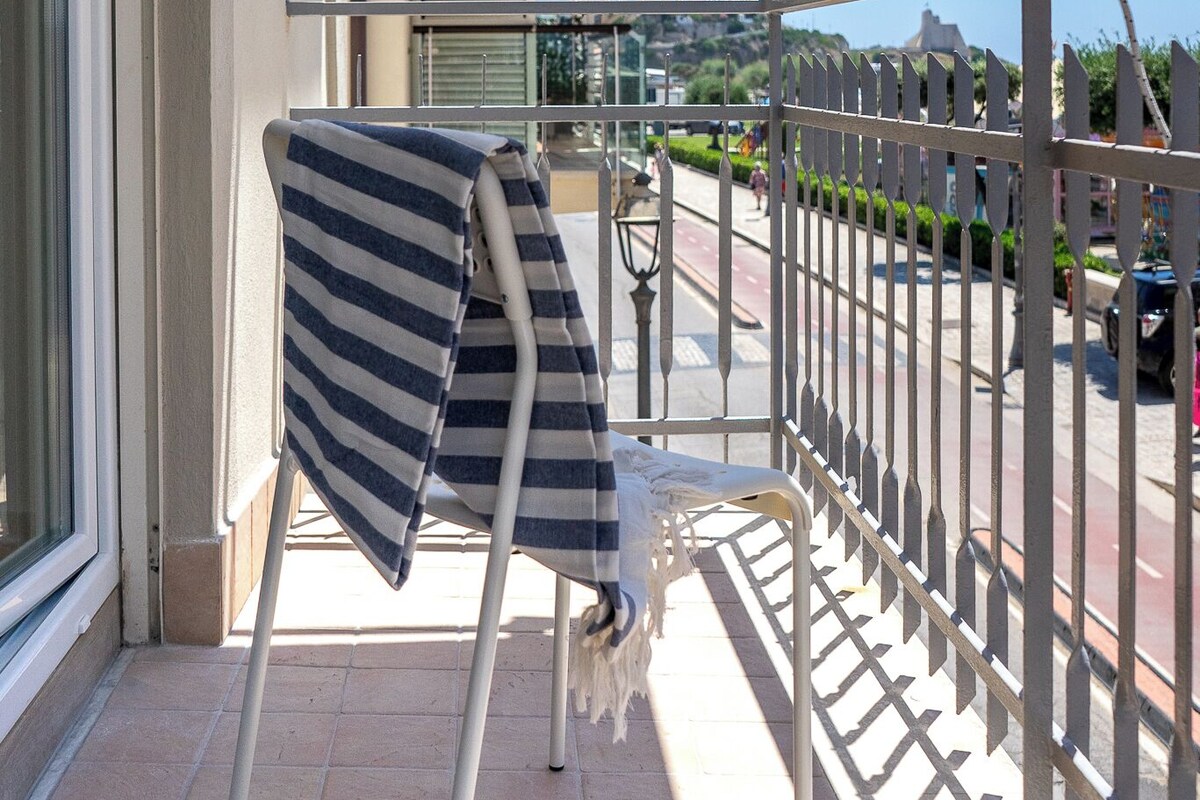 A balcony with a metal railing, a chair, and a striped towel draped over it.