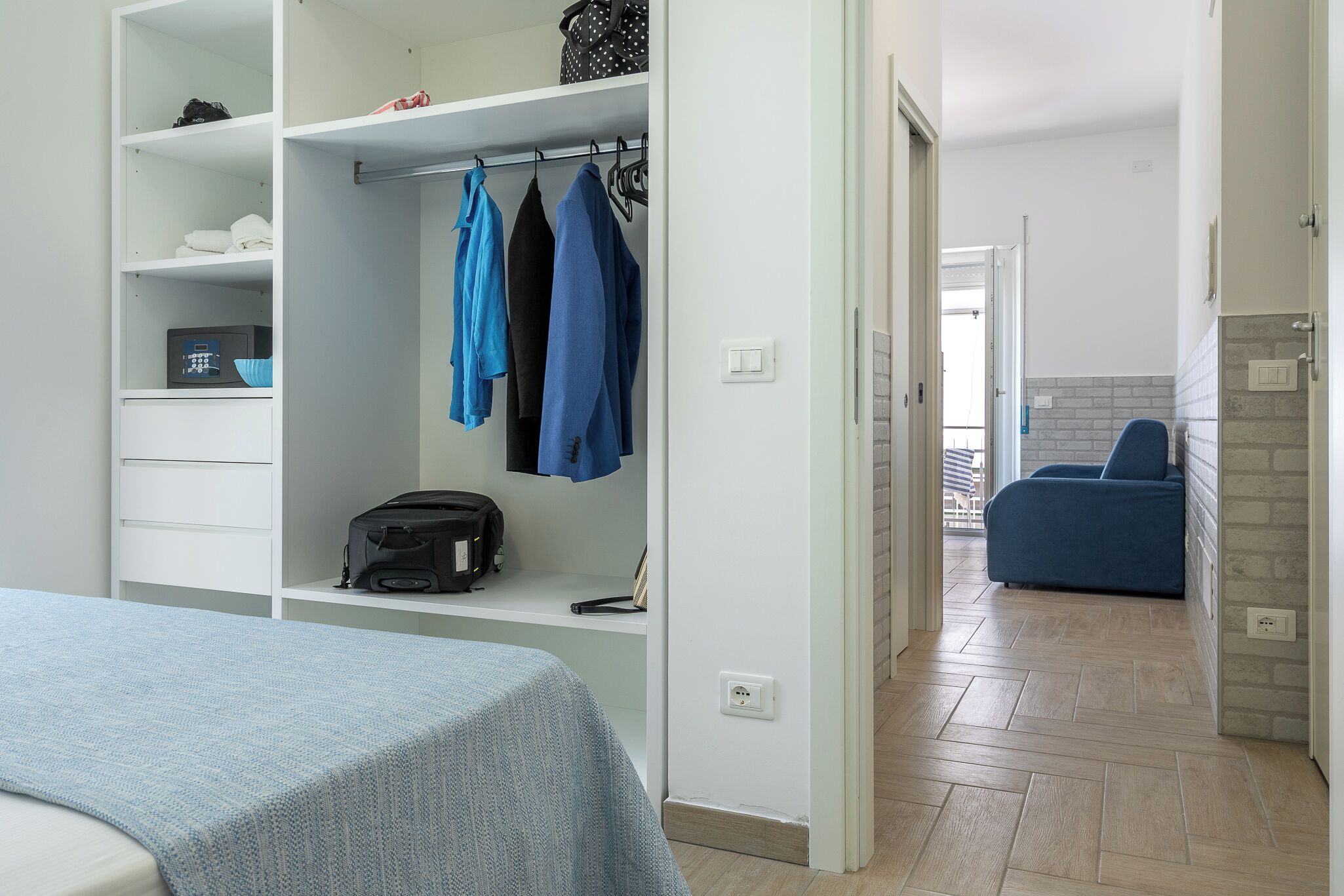 Un dormitorio con cama, armario y una zona de estar con una silla.