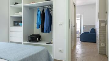 Un dormitorio con cama, armario y una zona de estar con una silla.