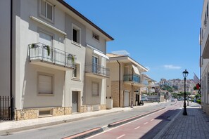 A street view with buildings featuring balconies, a clear sky, and a pedestrian sidewalk. - Casa Canzatora (Sperlonga)