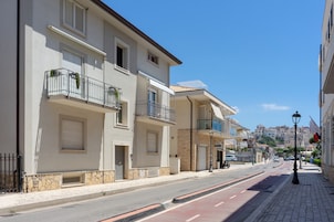 Una vista di una strada con edifici dotati di balconi, cielo sereno e marciapiede.