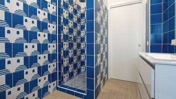 A bathroom with blue and white patterned tiles, a shower area, and a white sink with a mirror.