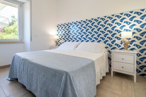 A bedroom with a bed, nightstands, a lamp, and a patterned wall. - Casa Canzatora (Sperlonga)