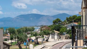 Un pueblo costero con una calle pavimentada, edificios y montañas al fondo.