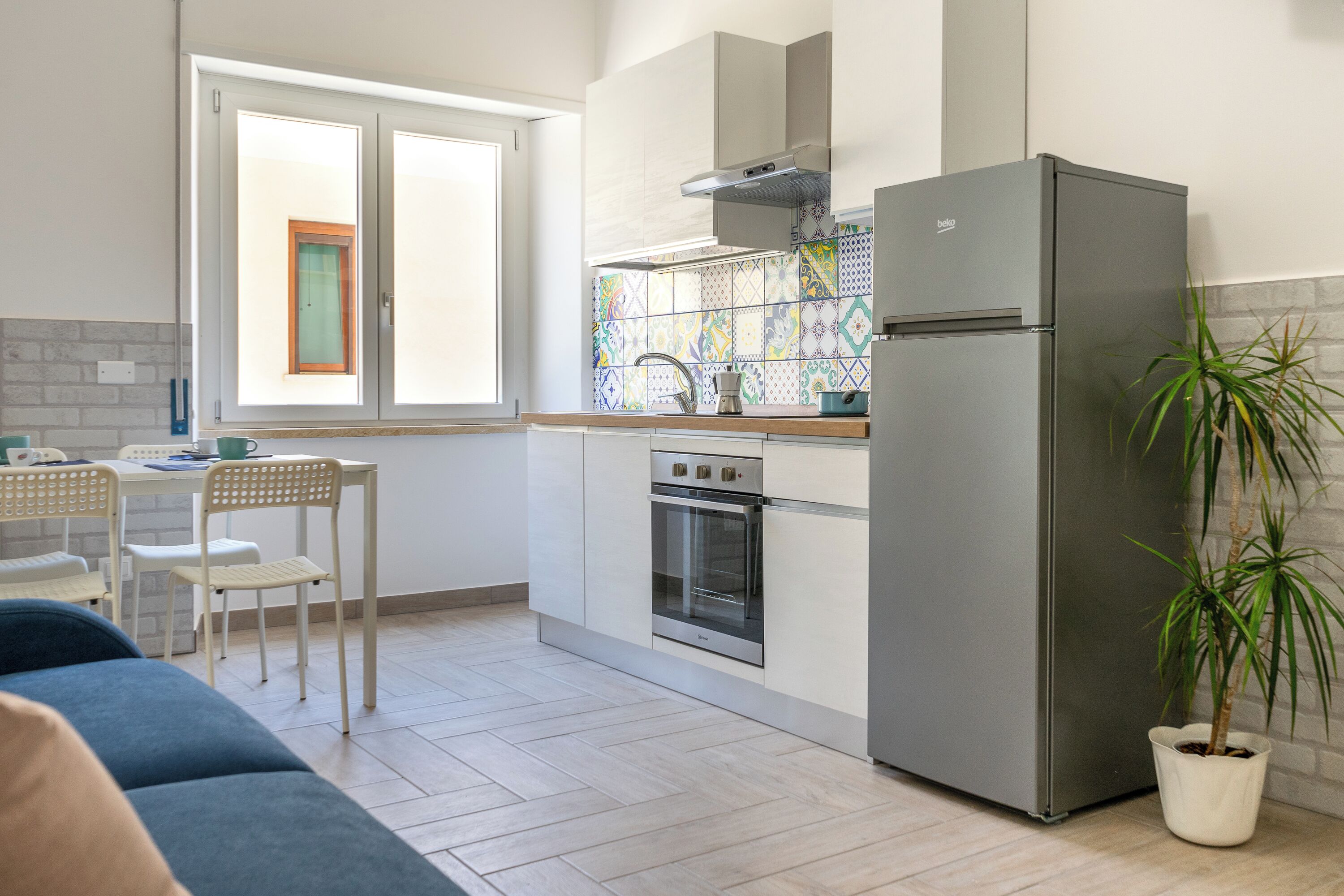 Una cucina compatta con forno a incasso, frigorifero in acciaio inox e una finestra vista esterna.