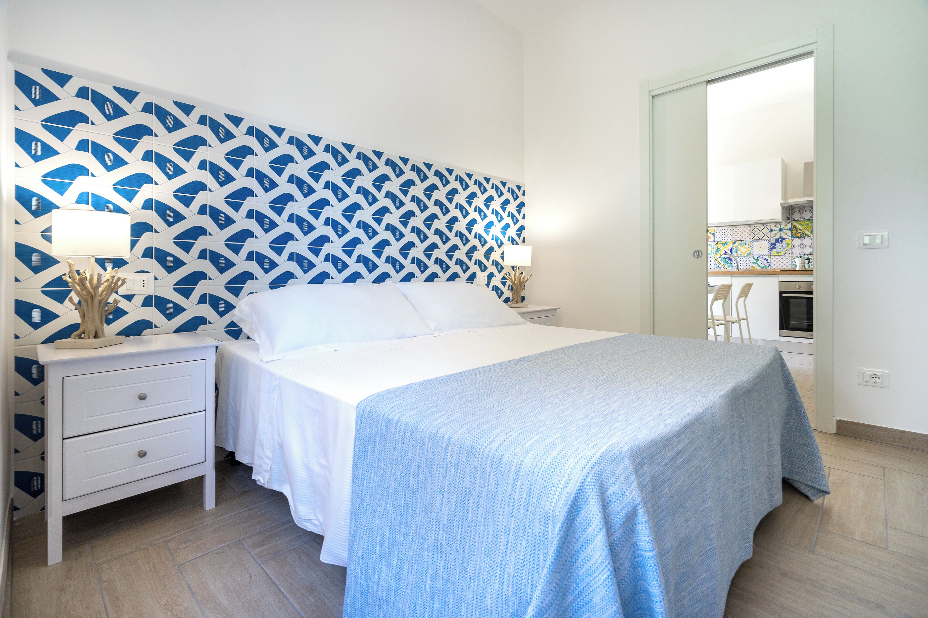 Un dormitorio con una cama, mesitas de noche y un papel tapiz estampado.
