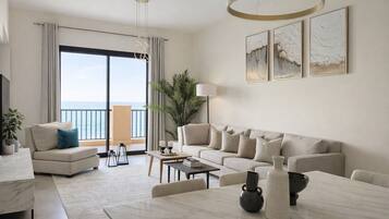 Un salon moderne avec un canapé, une table basse et une vue sur la mer grâce à de grandes fenêtres.