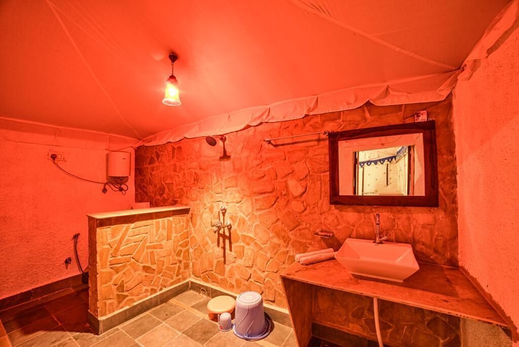 A bathroom with a stone wall, a sink, a mirror, and a shower area.