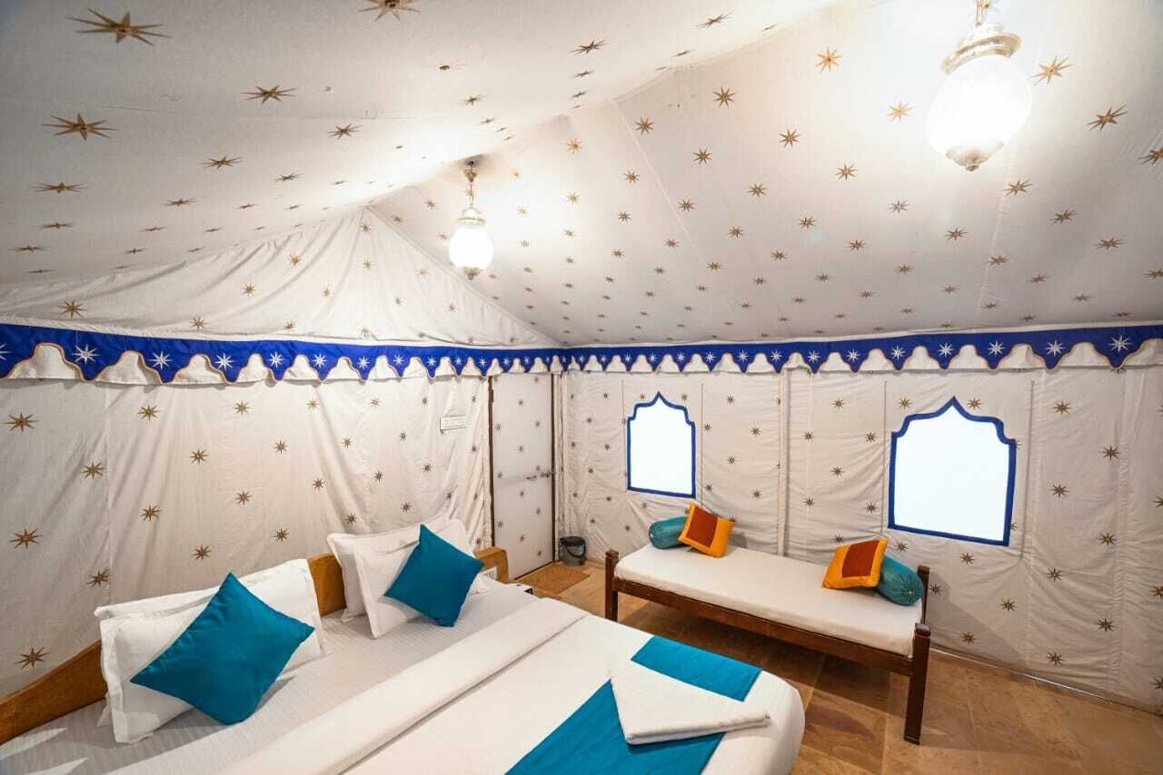 A tented room with two beds, star-patterned walls, and a canopy.
