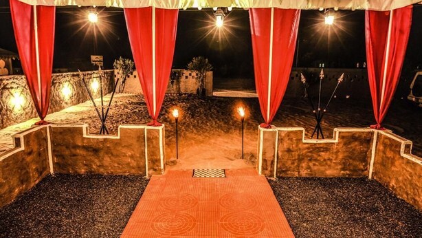 An outdoor stage with red curtains, a patterned carpet, and spotlights.