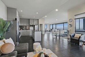 A spacious living area with a kitchen, dining space, and a view of the city. - Oceanview Oasis - Close to CBD and Airport (Sandy Bay)