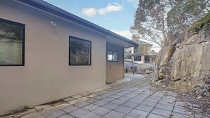 A building with a flat roof, large windows, and a paved walkway. - Spacious Sandy Bay Retreat with Water Views (Sandy Bay)