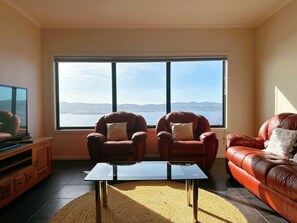 A living room with two armchairs, a sofa, a coffee table, and a television. - Oceanview Oasis - Close to CBD and Airport (Sandy Bay)